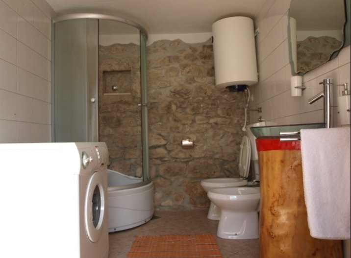 Badkamer met douche en wasmachine